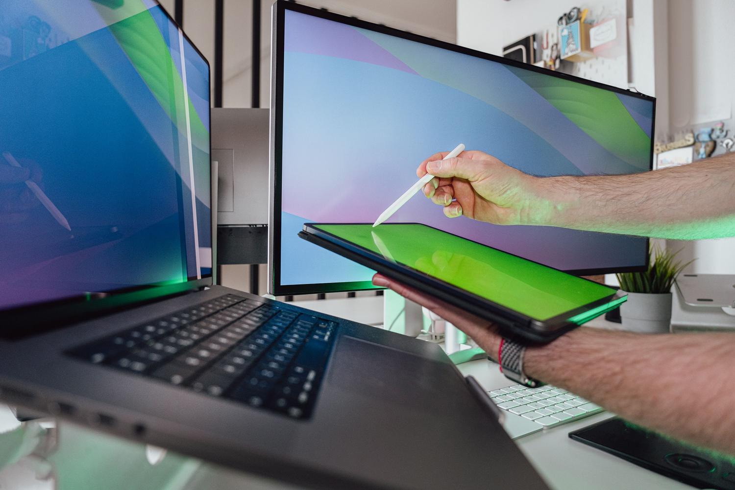 Professional technician using a stylus to audit and analyze technical data on a tablet and monitor setup. Professional technician using a stylus to audit and analyze technical data on a tablet and monitor setup.