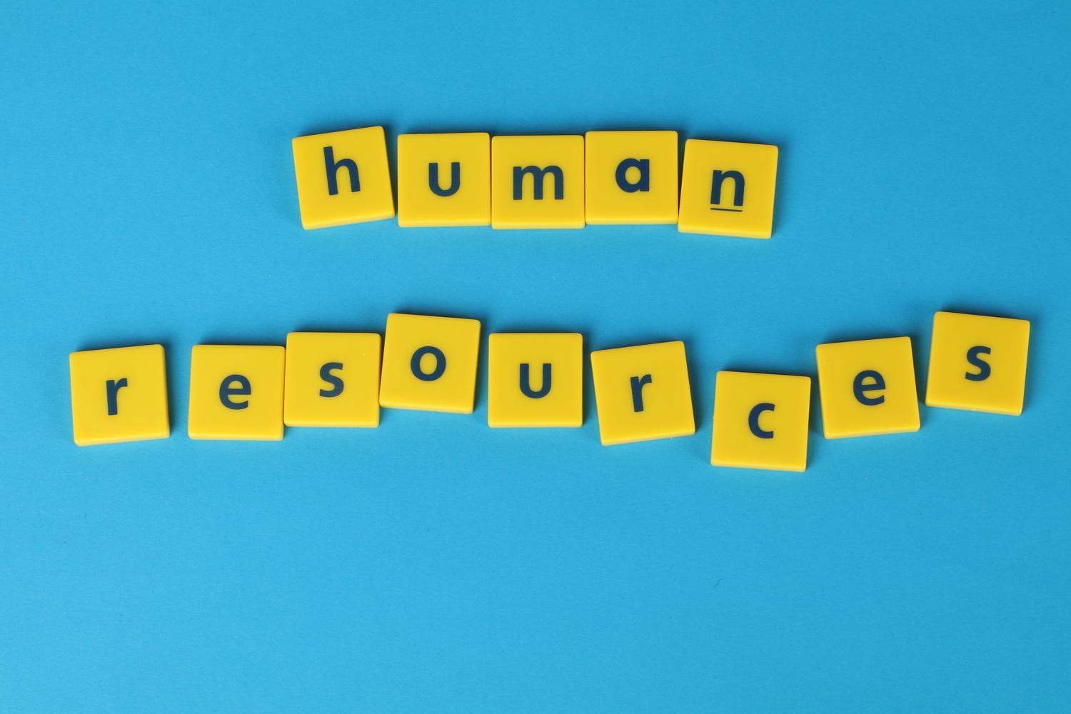 Fichas de letras amarillas formando la frase 'human resources' sobre un fondo azul vibrante, representando la gestión de recursos humanos. Fichas de letras amarillas formando la frase 'human resources' sobre un fondo azul vibrante, representando la gestión de recursos humanos.