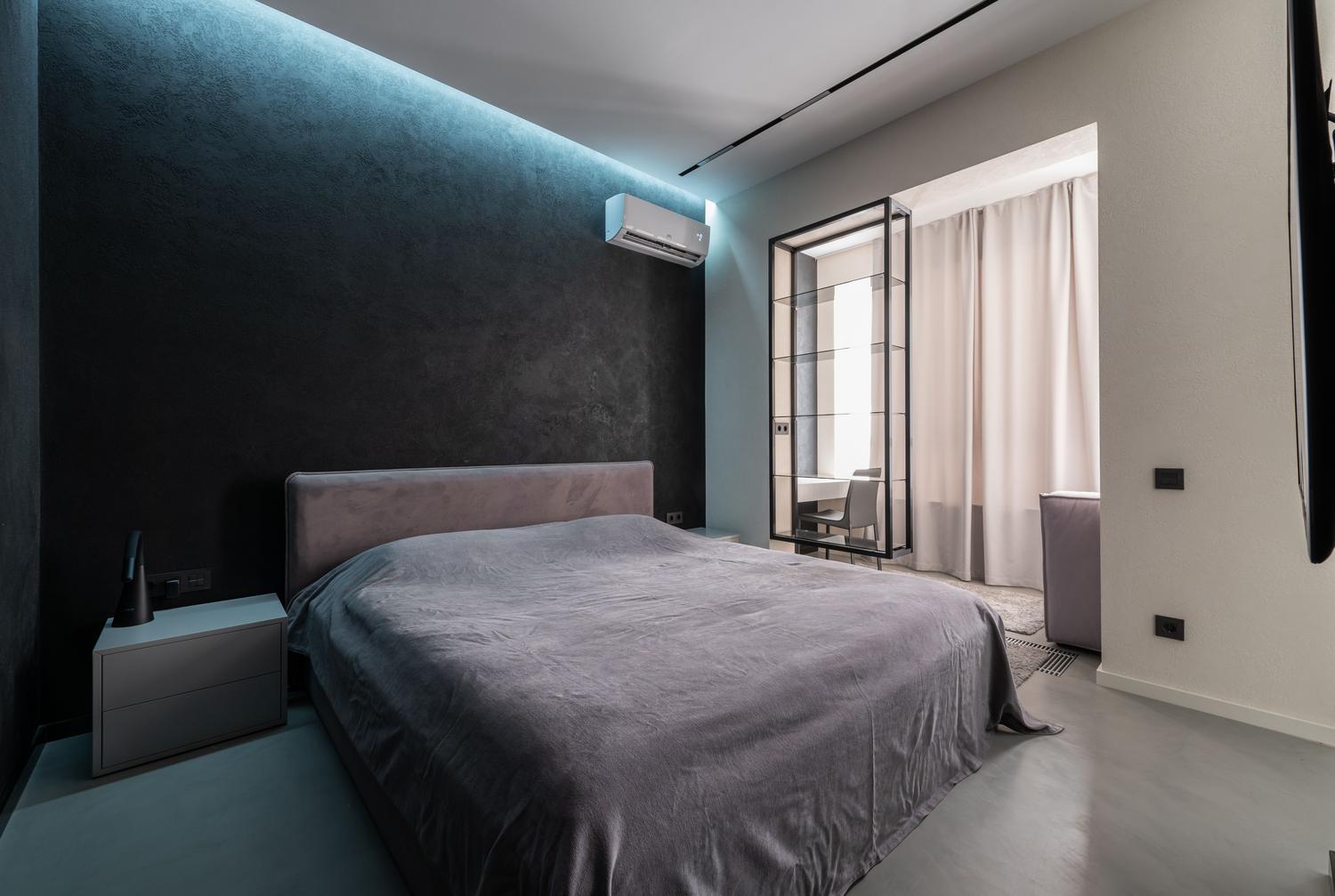 Dormitorio moderno con aire acondicionado inteligente instalado en la pared Dormitorio contemporáneo y espacioso con una cama confortable y un aire acondicionado instalado en la pared.