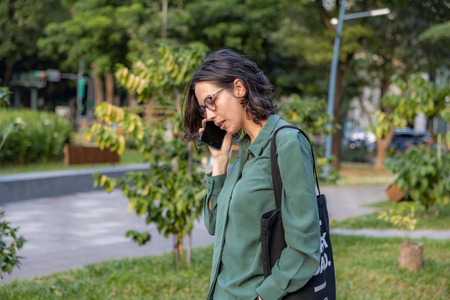 Mujer joven hablando por teléfono mientras camina por un parque, representando el uso cotidiano y natural de los smartphones. Mujer joven hablando por teléfono mientras camina por un parque, representando el uso cotidiano y natural de los smartphones.