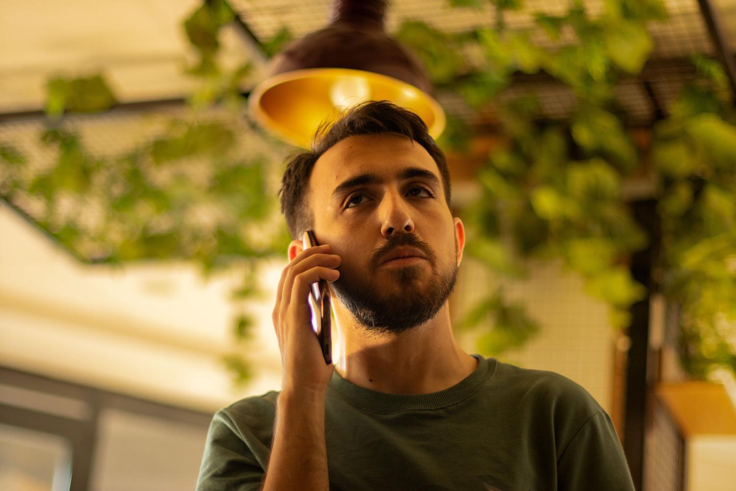 Hombre joven con expresión seria hablando por teléfono en un interior moderno, ideal para ilustrar la seguridad y la importancia de dejar constancia legal. Hombre joven con expresión seria hablando por teléfono en un interior moderno, ideal para ilustrar la seguridad y la importancia de dejar constancia legal.