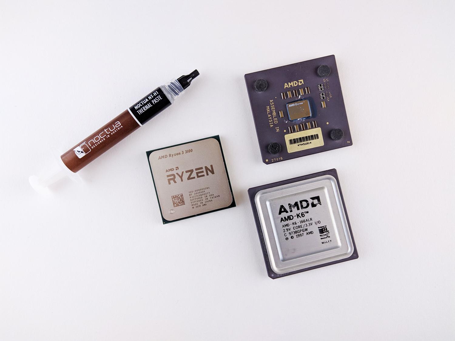 Conjunto de procesadores AMD de diferentes generaciones junto a pasta térmica Noctua sobre un fondo blanco. Conjunto de procesadores AMD de diferentes generaciones junto a pasta térmica Noctua sobre un fondo blanco.