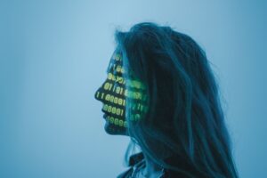 Silueta de una mujer con código binario proyectado en su rostro, representando la intersección entre la identidad digital y la inteligencia artificial en un entorno de ciberseguridad.