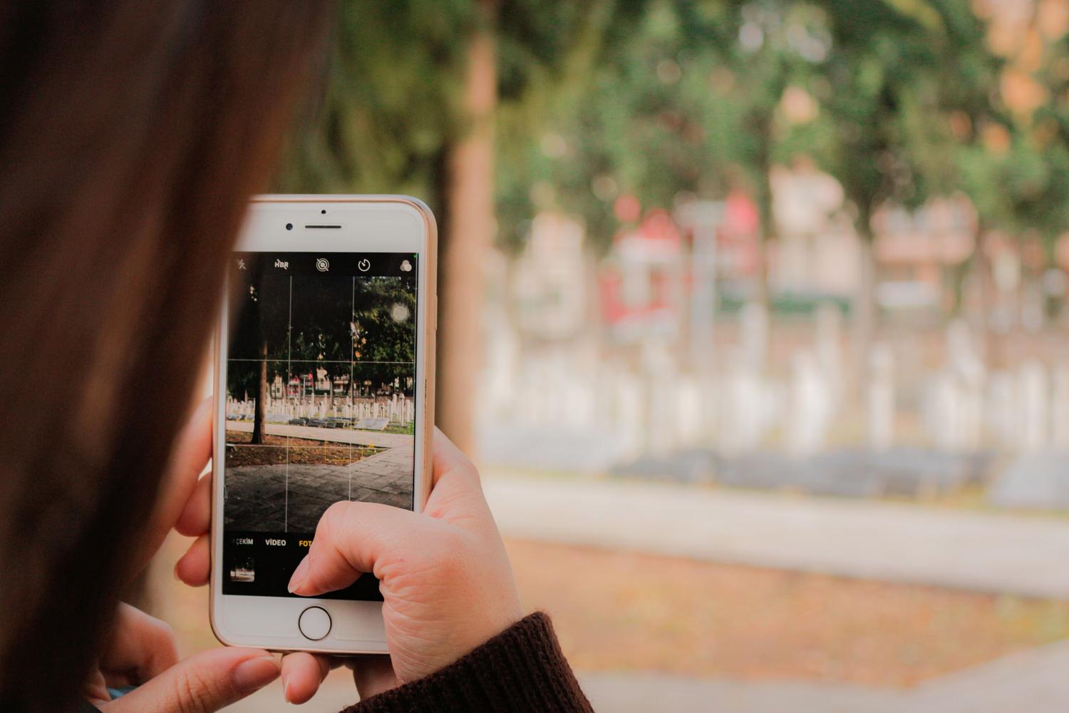 Detalle de una persona componiendo una fotografía de un parque con un móvil, utilizando la cuadrícula para lograr un encuadre profesional. Detalle de una persona componiendo una fotografía de un parque con un móvil, utilizando la cuadrícula para lograr un encuadre profesional.