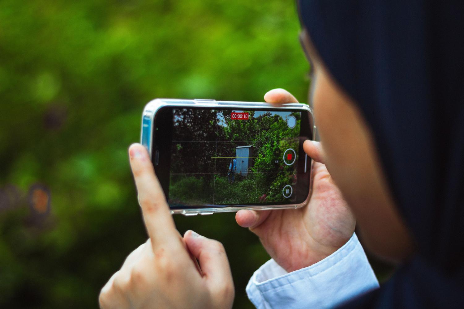 Persona grabando un vídeo en modo profesional con un smartphone, mostrando la interfaz de grabación, el temporizador y la regla de los tercios. Persona grabando un vídeo en modo profesional con un smartphone, mostrando la interfaz de grabación, el temporizador y la regla de los tercios.