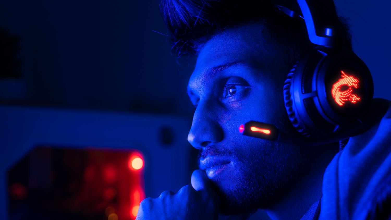 Jugador concentrado utilizando auriculares profesionales en un entorno con iluminación RGB azul y roja, resaltando la inmersión en el juego. Jugador concentrado utilizando auriculares profesionales en un entorno con iluminación RGB azul y roja, resaltando la inmersión en el juego.