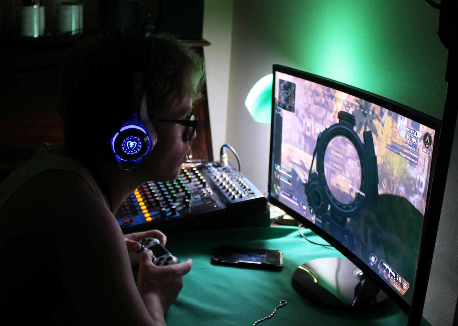 Setup de gaming avanzado con monitor curvo, auriculares con LED azul y consola de audio profesional bajo una atmósfera de luces verdes. Setup de gaming avanzado con monitor curvo, auriculares con LED azul y consola de audio profesional bajo una atmósfera de luces verdes.