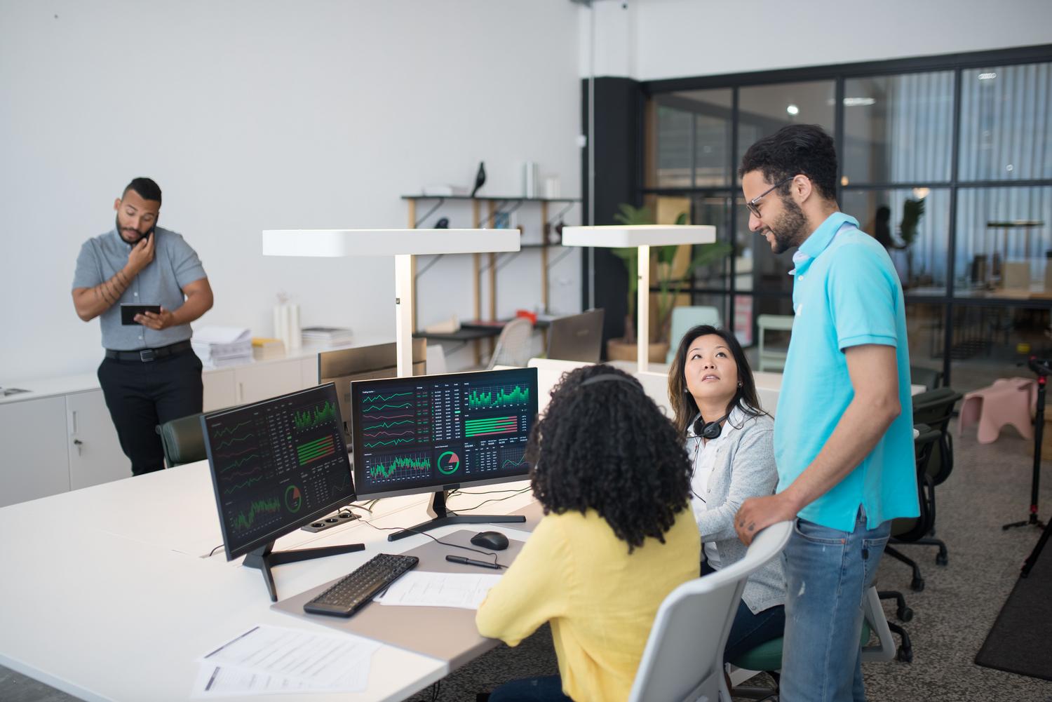 Profesionales trabajando juntos en un entorno de oficina moderno con monitores duales mostrando visualizaciones de datos. Profesionales trabajando juntos en un entorno de oficina moderno con monitores duales mostrando visualizaciones de datos.