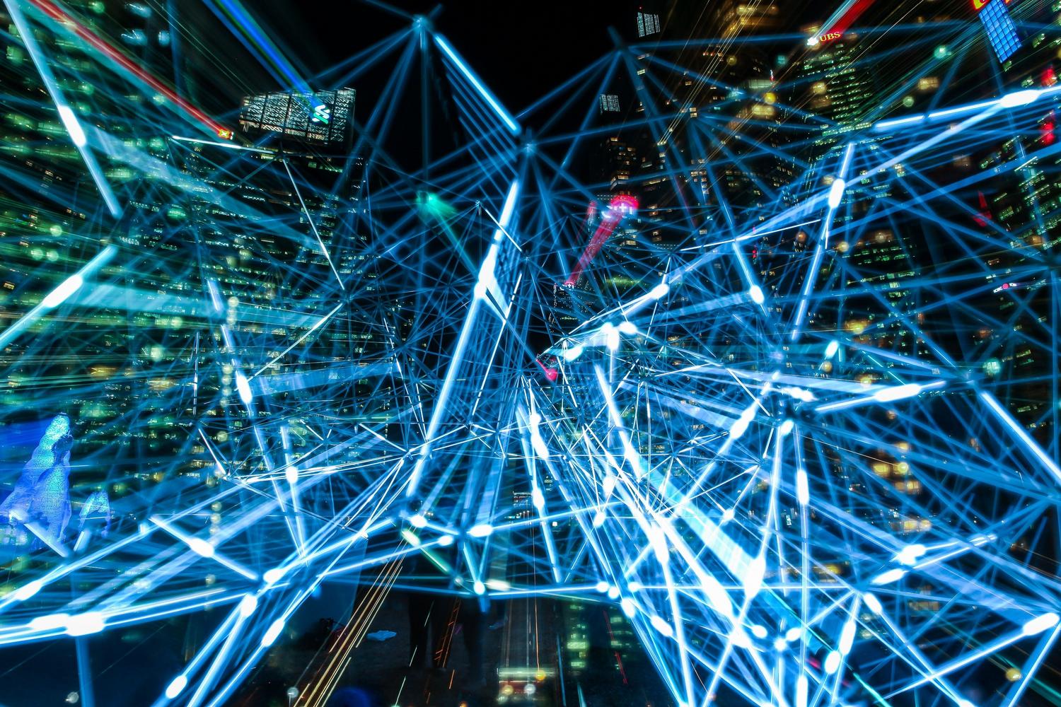 Representación visual de una ciudad hiperconectada con redes neuronales de luz azul simbolizando el IoT y el flujo de datos. Representación visual de una ciudad hiperconectada con redes neuronales de luz azul simbolizando el IoT y el flujo de datos.