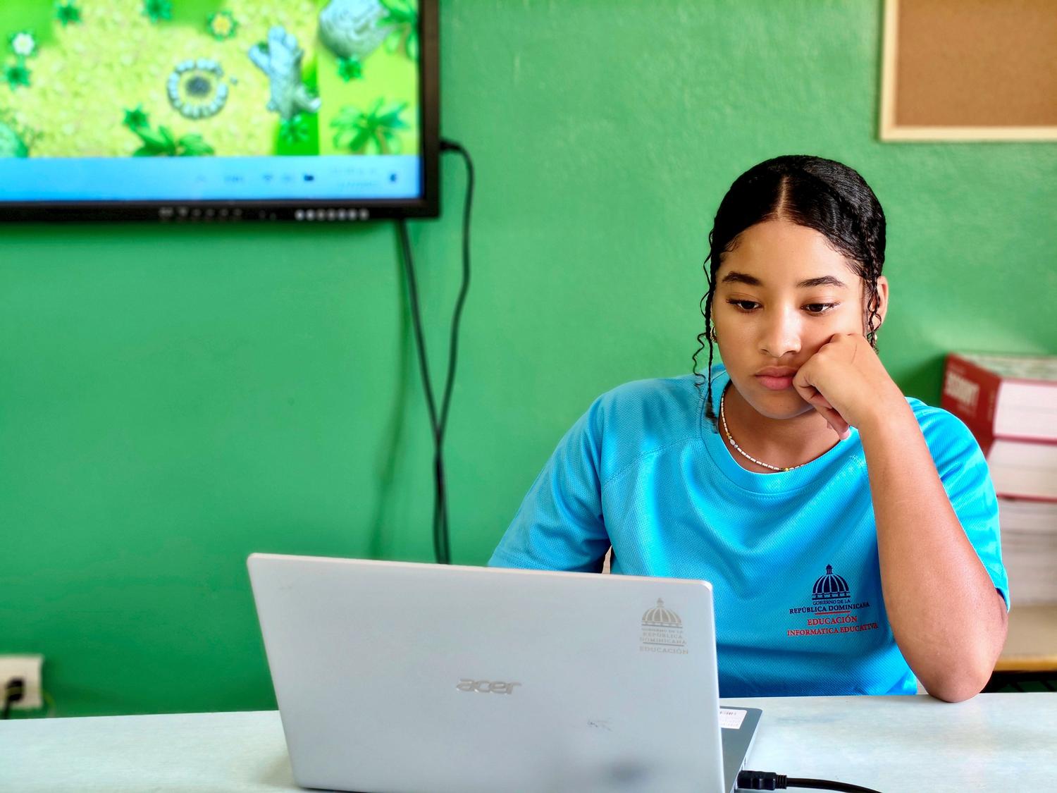 Estudiante adolescente utilizando una laptop proporcionada por el centro educativo en un aula de informática. Estudiante adolescente utilizando una laptop proporcionada por el centro educativo en un aula de informática.
