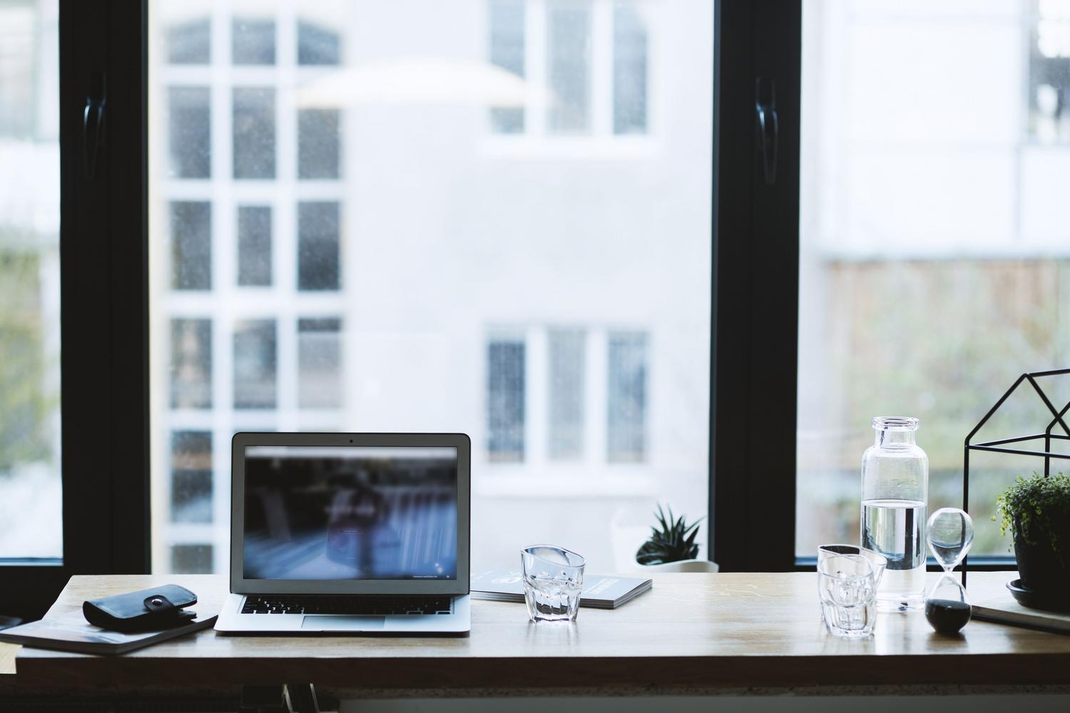 Espacio de trabajo profesional y minimalista con un ordenador portátil moderno sobre una mesa de madera. Espacio de trabajo profesional y minimalista con un ordenador portátil moderno sobre una mesa de madera.