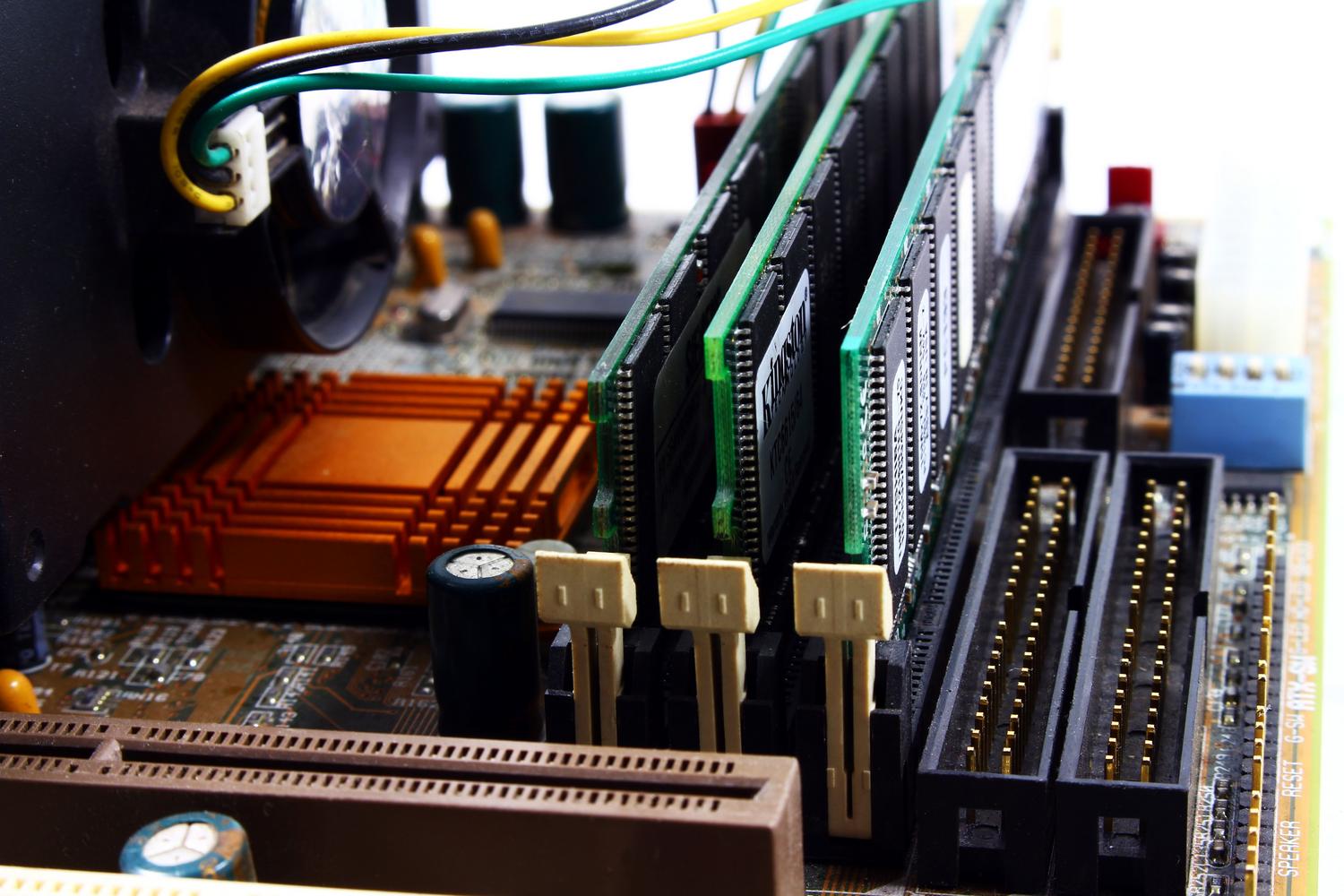 Vista detallada de una placa base de PC mostrando la instalación de memoria RAM y sistemas de refrigeración. Vista detallada de una placa base de PC mostrando la instalación de memoria RAM y sistemas de refrigeración.