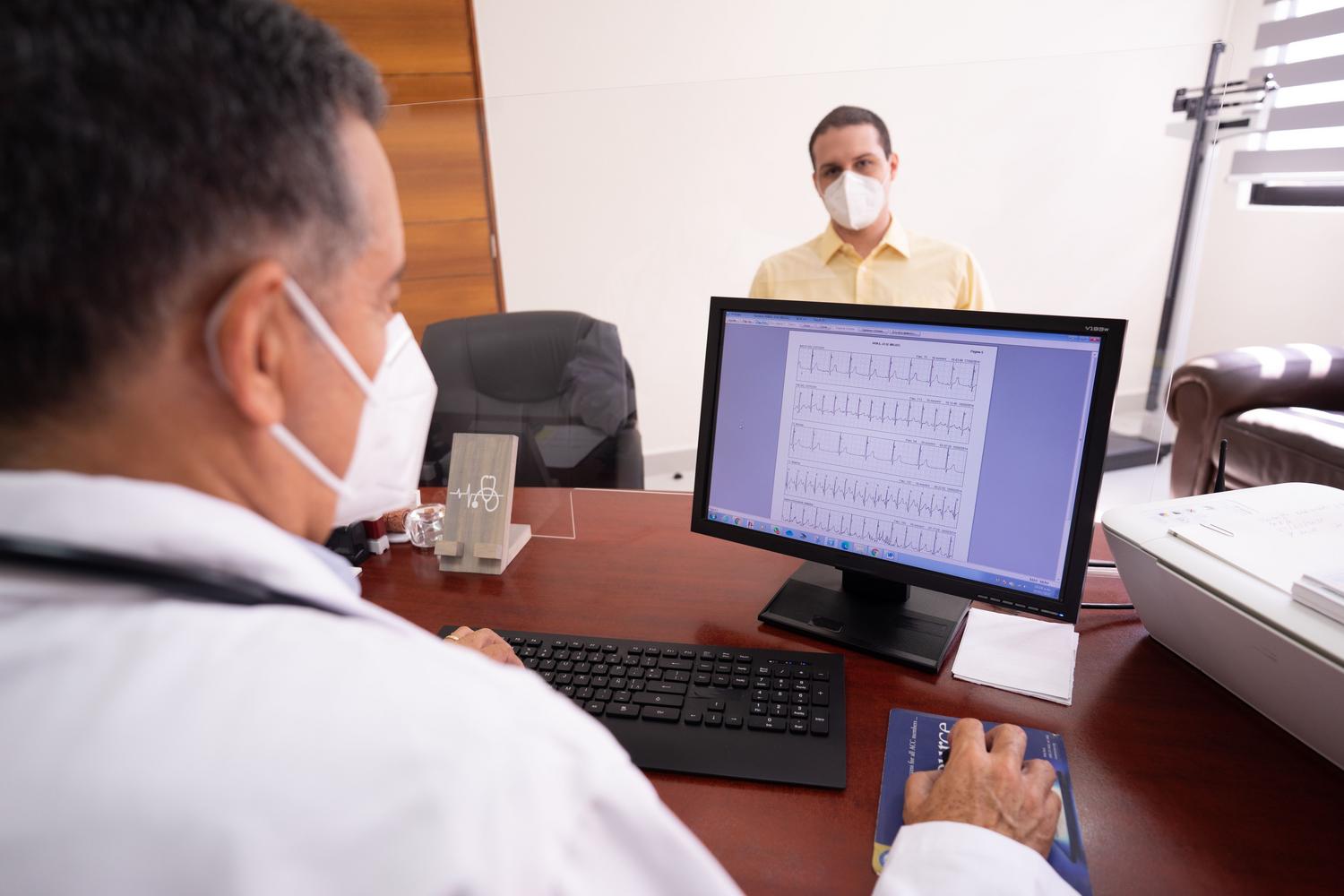 Médico analizando un electrocardiograma digital en pantalla durante una consulta, mostrando la fusión de la informática y el diagnóstico médico. Médico analizando un electrocardiograma digital en pantalla durante una consulta, mostrando la fusión de la informática y el diagnóstico médico.