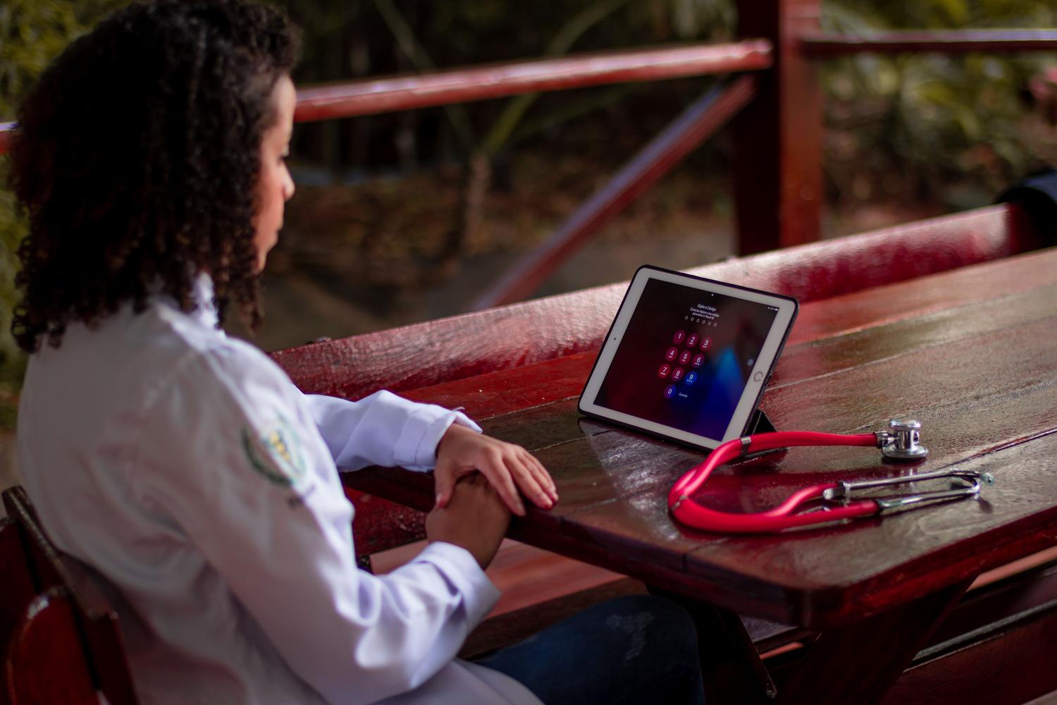 Profesional sanitaria utilizando una tablet y un estetoscopio en un entorno exterior, representando la movilidad y el acceso a la salud digital en espacios públicos. Profesional sanitaria utilizando una tablet y un estetoscopio en un entorno exterior, representando la movilidad y el acceso a la salud digital en espacios públicos.
