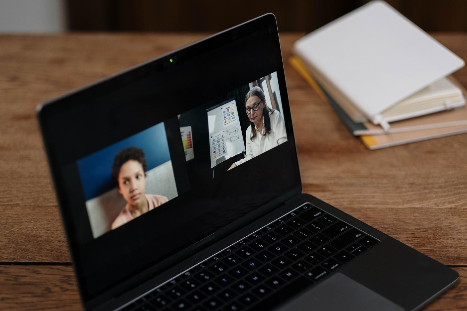 Pantalla de portátil mostrando una clase interactiva online con una profesora y un alumno. Pantalla de portátil mostrando una clase interactiva online con una profesora y un alumno.