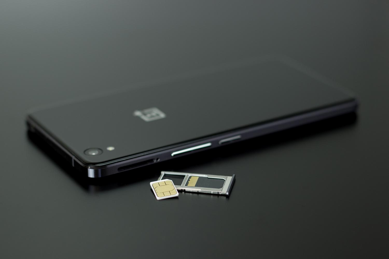Recuperación del número de teléfono en WhatsApp Primer plano de un smartphone con una tarjeta SIM, ilustrando la recuperación del número de teléfono.
