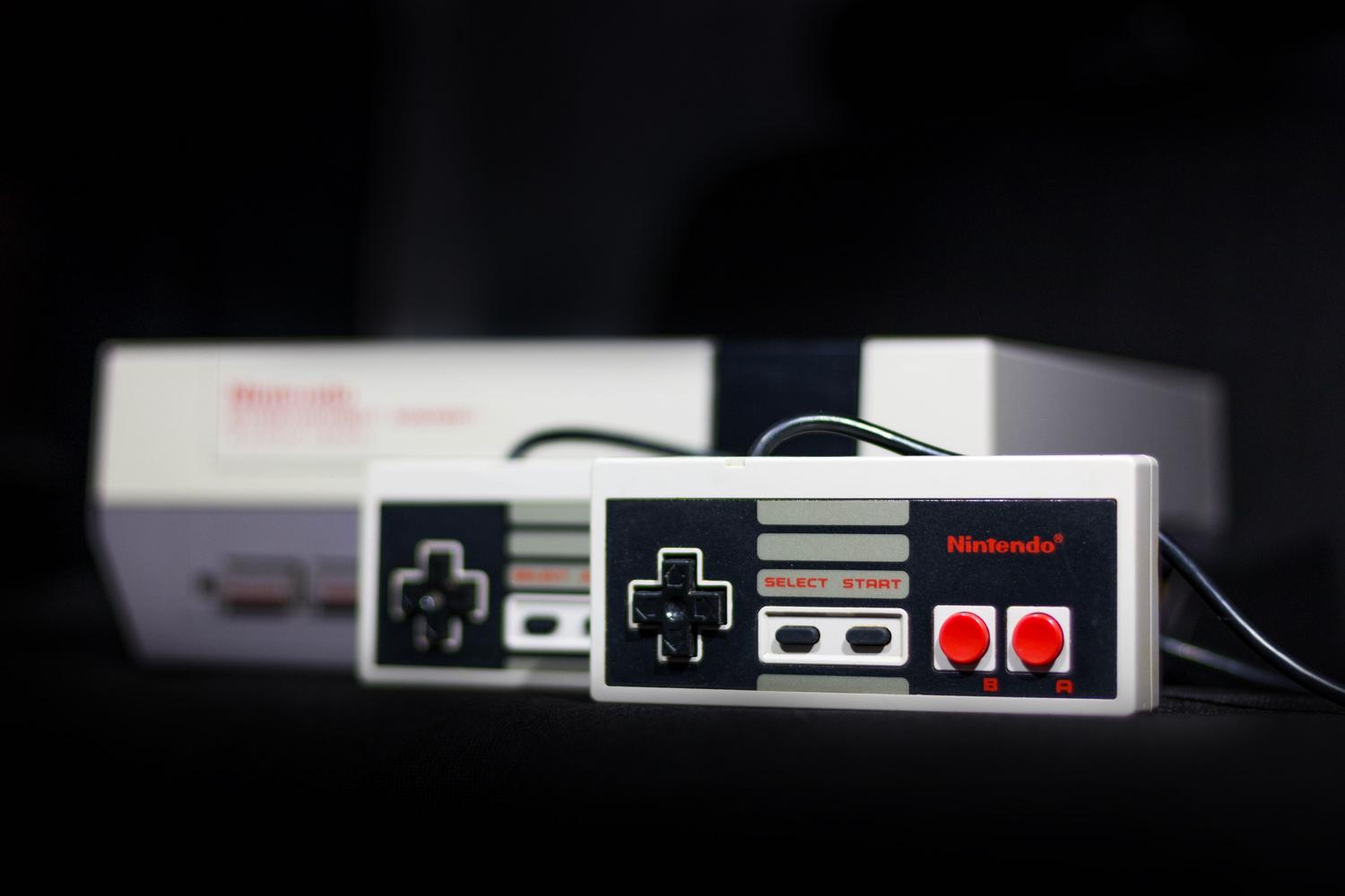 Close-up of a classic Nintendo NES console and controllers, representing the 8-bit era of the 80s. Close-up of a classic Nintendo NES console and controllers, representing the 8-bit era of the 80s.
