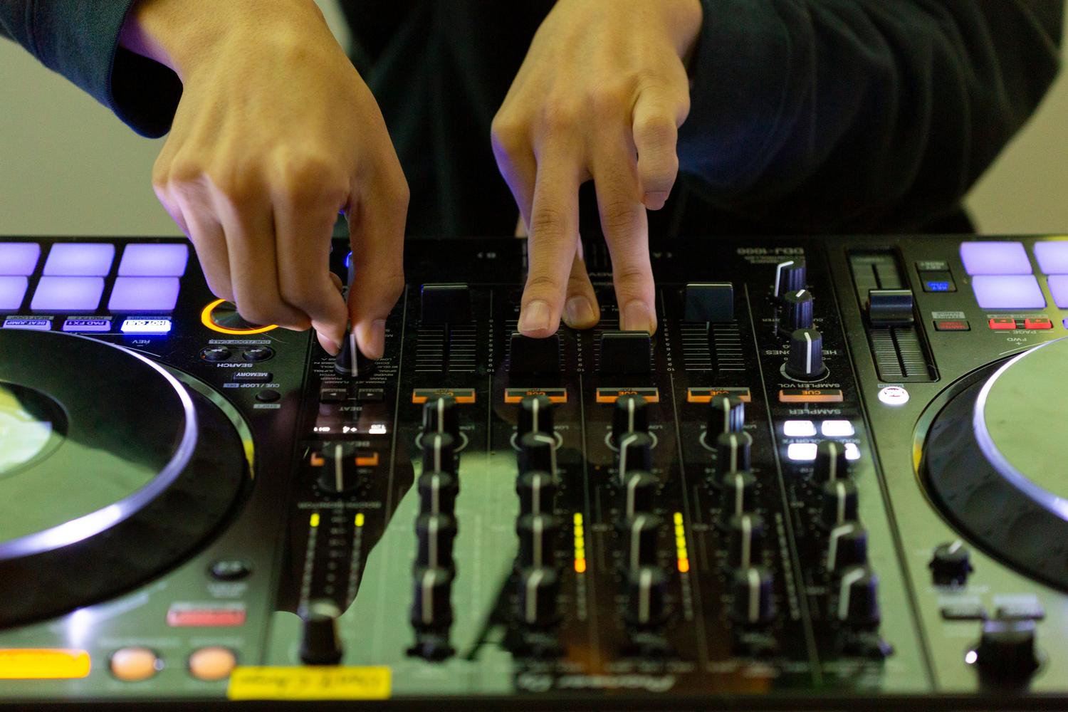 Manos de un DJ mezclando música en una mesa de mezclas Manos de un DJ mezclando música en una mesa de mezclas
