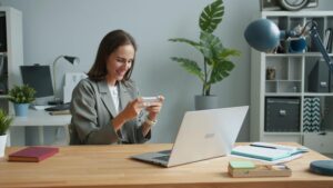 Mujer trabajando desde casa usando su smartphone y ordenador portátil para gestionar sus comunicaciones.