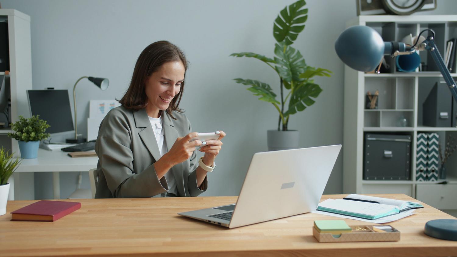 Mujer trabajando desde casa usando su smartphone y ordenador portátil para gestionar sus comunicaciones. Mujer trabajando desde casa usando su smartphone y ordenador portátil para gestionar sus comunicaciones.