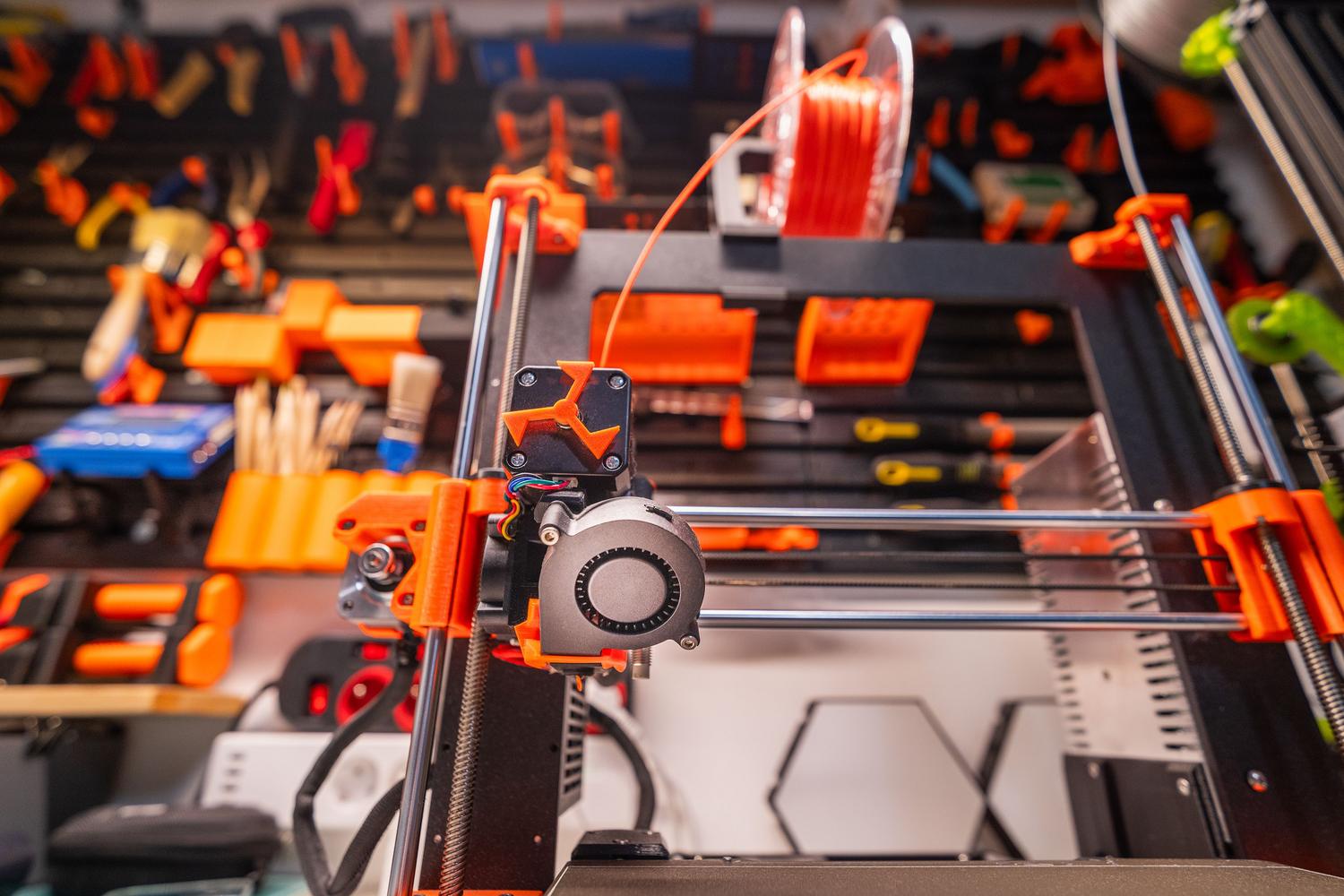 Estación de trabajo doméstica para impresión 3D con impresora y tablero de herramientas organizado.