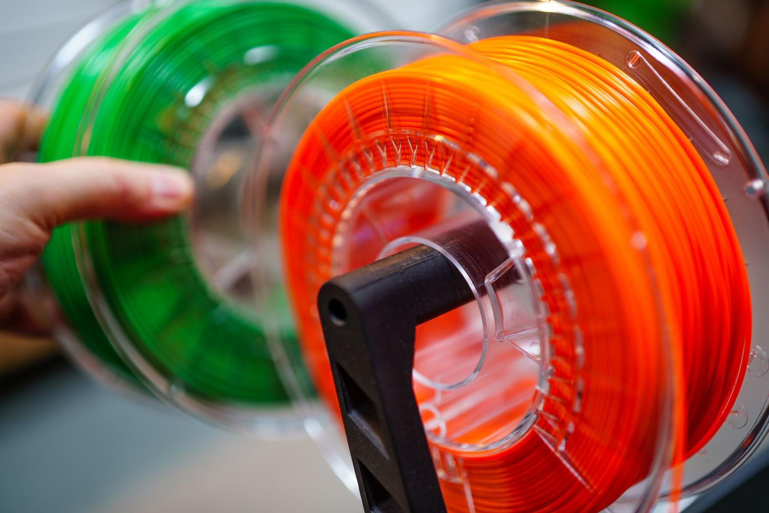 Bobinas de filamento PLA de colores naranja y verde para impresora 3D. Bobinas de filamento PLA de colores naranja y verde para impresora 3D.
