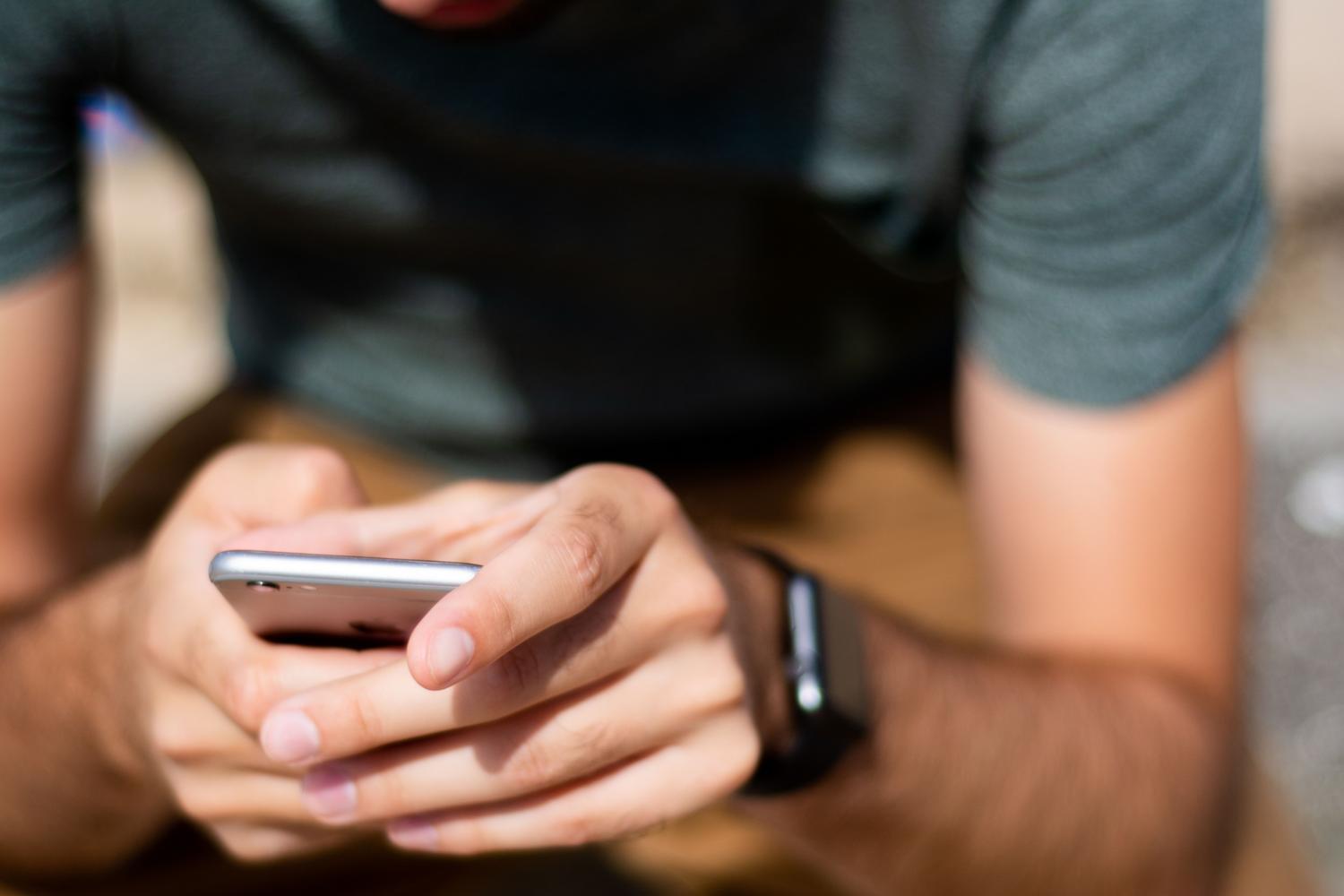 Primer plano de manos utilizando un iPhone al aire libre, ilustrando la movilidad y el uso cotidiano de las automatizaciones. Primer plano de manos utilizando un iPhone al aire libre, ilustrando la movilidad y el uso cotidiano de las automatizaciones.
