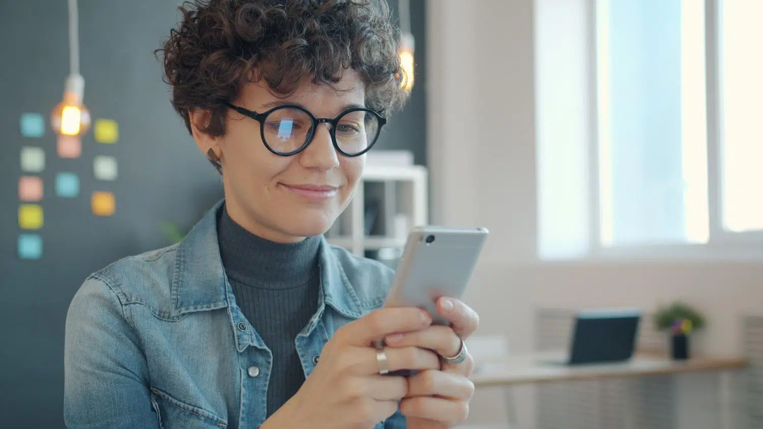 Mujer profesional usando un iPhone en una oficina moderna, representando la productividad y eficiencia de los atajos. Mujer profesional usando un iPhone en una oficina moderna, representando la productividad y eficiencia de los atajos.