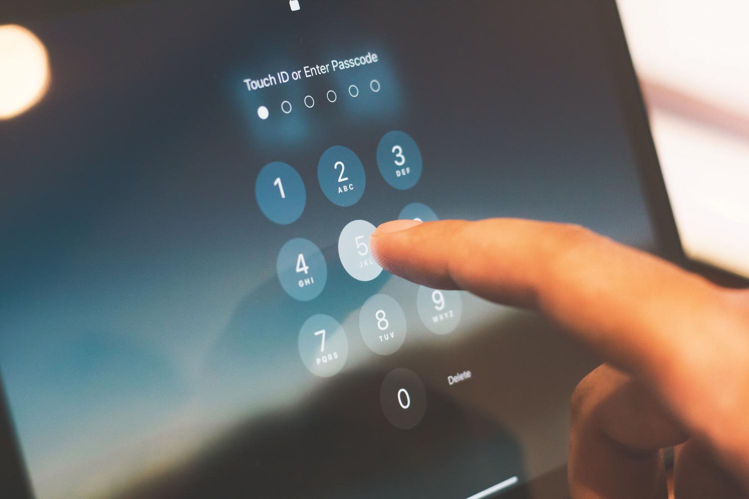 Mano introduciendo un código PIN de seguridad en la pantalla de un teléfono móvil para acceder a una aplicación bloqueada. Mano introduciendo un código PIN de seguridad en la pantalla de un teléfono móvil para acceder a una aplicación bloqueada.