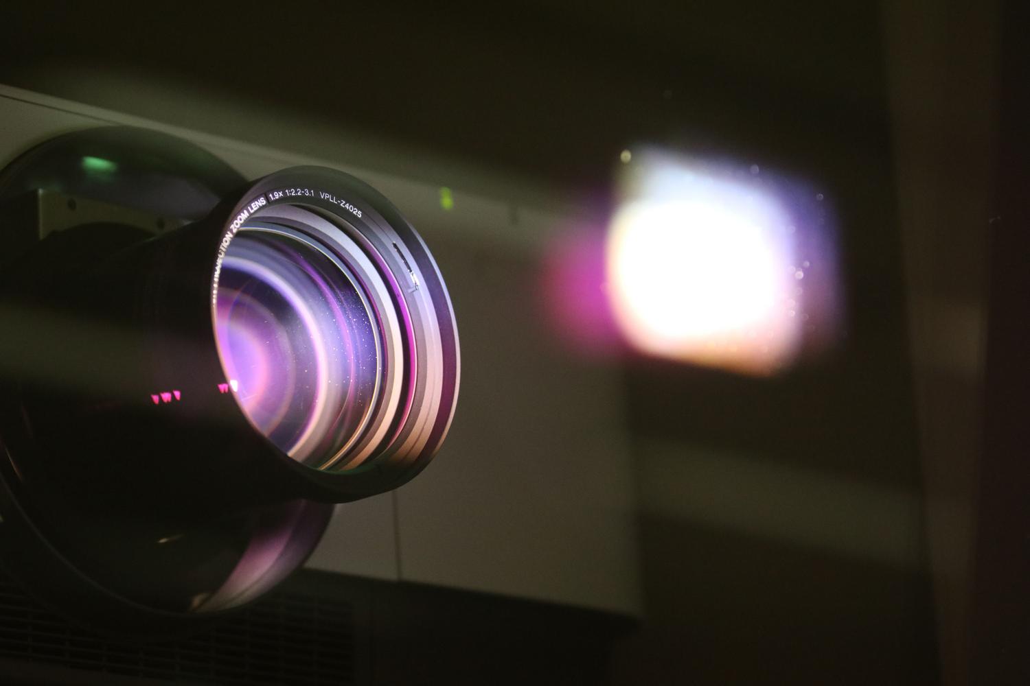 Detalle del lente de un proyector con reflejos de luz, resaltando la importancia del cuidado de la óptica y los filtros. Detalle del lente de un proyector con reflejos de luz, resaltando la importancia del cuidado de la óptica y los filtros.