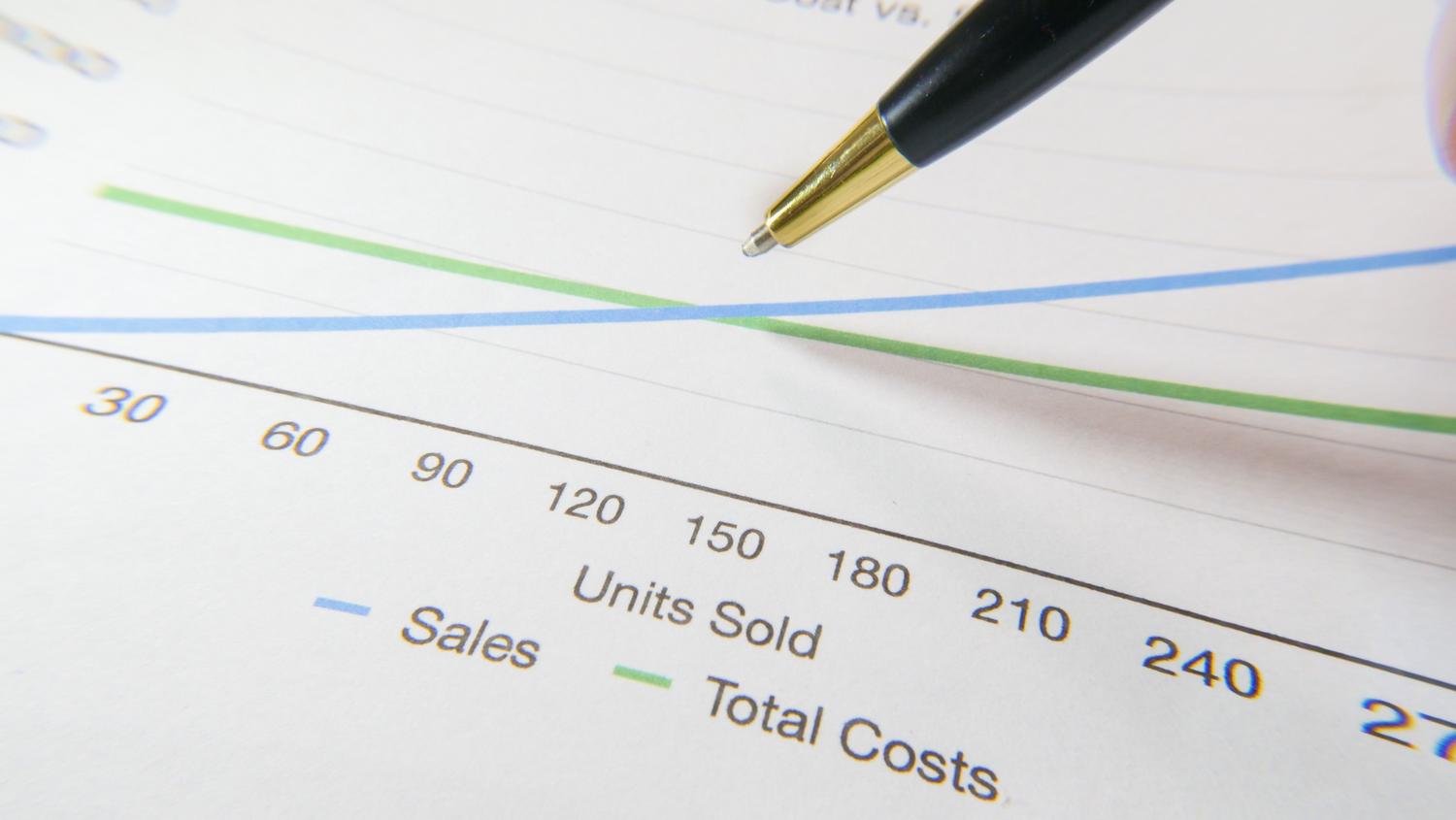Análisis de costes financieros con un gráfico de líneas y un bolígrafo señalando el gasto total, ideal para ilustrar la inversión en agentes de IA.