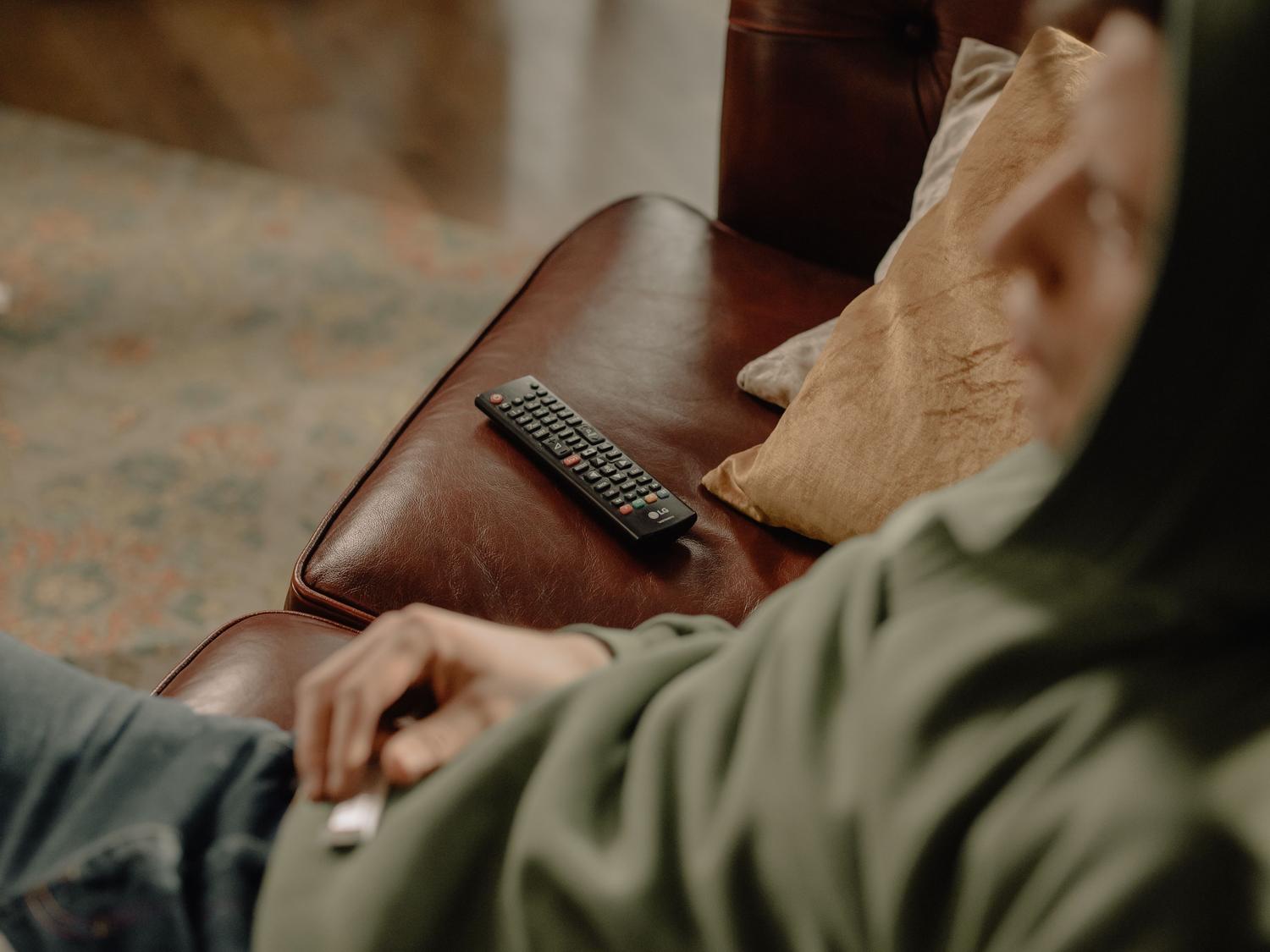 Hombre relajado en el sofá con un mando a distancia para controlar Netflix en una Smart TV Hombre relajado en el sofá con un mando a distancia para controlar Netflix en una Smart TV