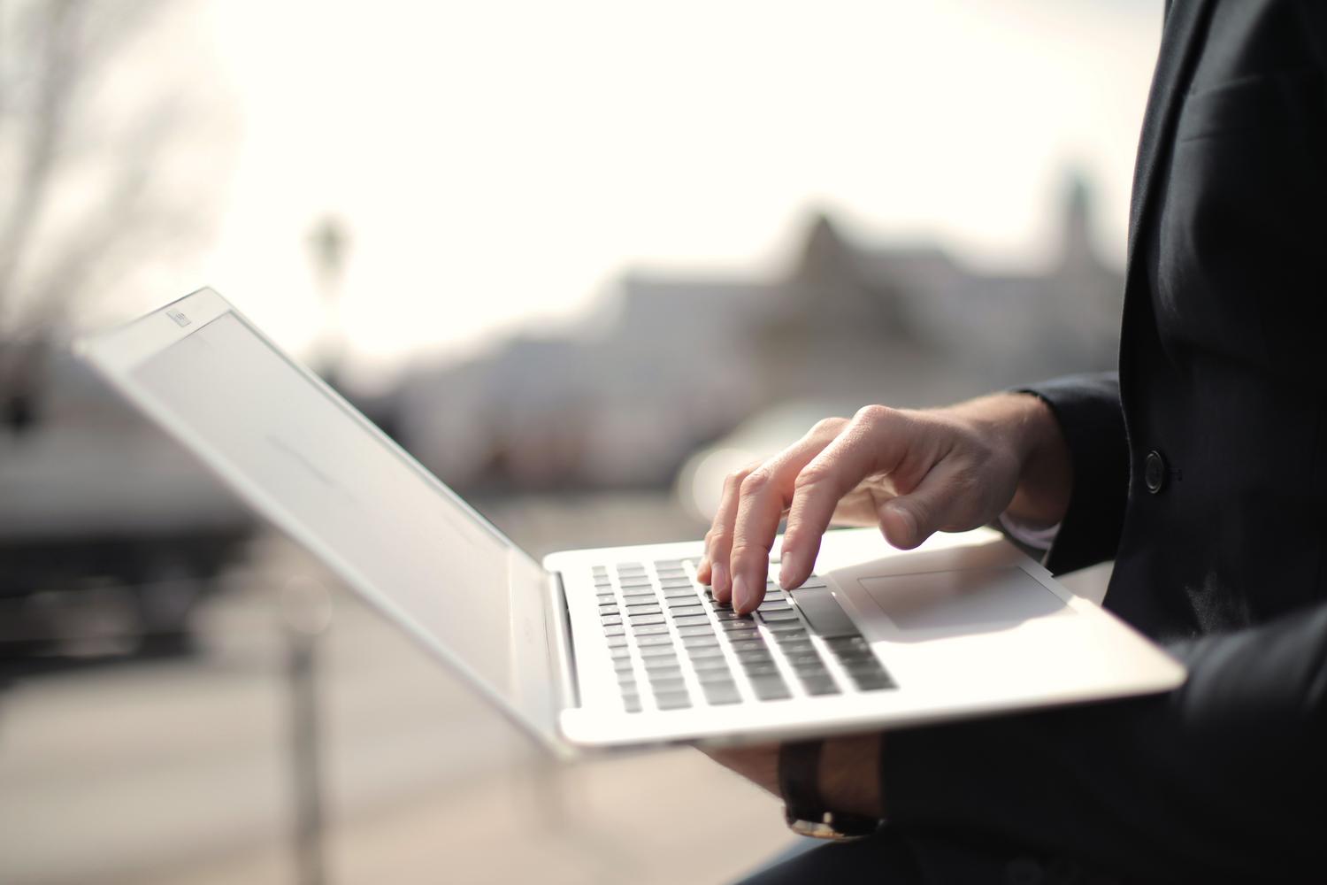 Empresario utilizando un ordenador portátil al aire libre, simbolizando el inicio de la gestión de negocios en la nube. Empresario utilizando un ordenador portátil al aire libre, simbolizando el inicio de la gestión de negocios en la nube.