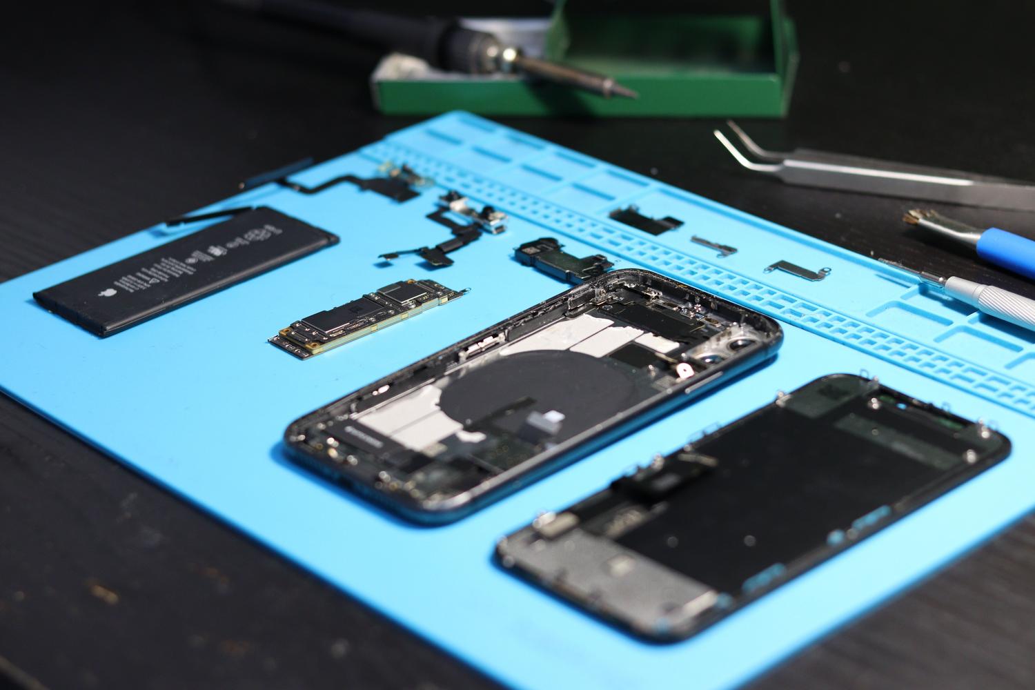 Herramientas de reparación y un smartphone desmontado en un banco de trabajo, ilustrando el proceso de reacondicionamiento profesional. Herramientas de reparación y un smartphone desmontado en un banco de trabajo, ilustrando el proceso de reacondicionamiento profesional.