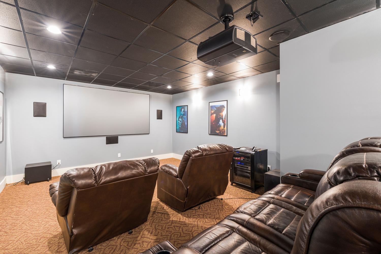 Lujoso sistema de cine en casa con asientos reclinables y equipo audiovisual avanzado, representando la inmersión del audio espacial.