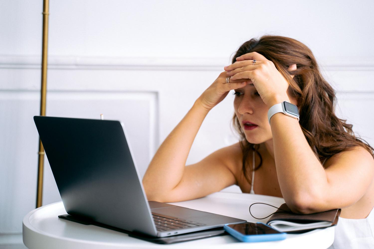 Mujer gestionando la seguridad de sus cuentas desde el móvil y el portátil tras la pérdida de su equipo. Mujer gestionando la seguridad de sus cuentas desde el móvil y el portátil tras la pérdida de su equipo.