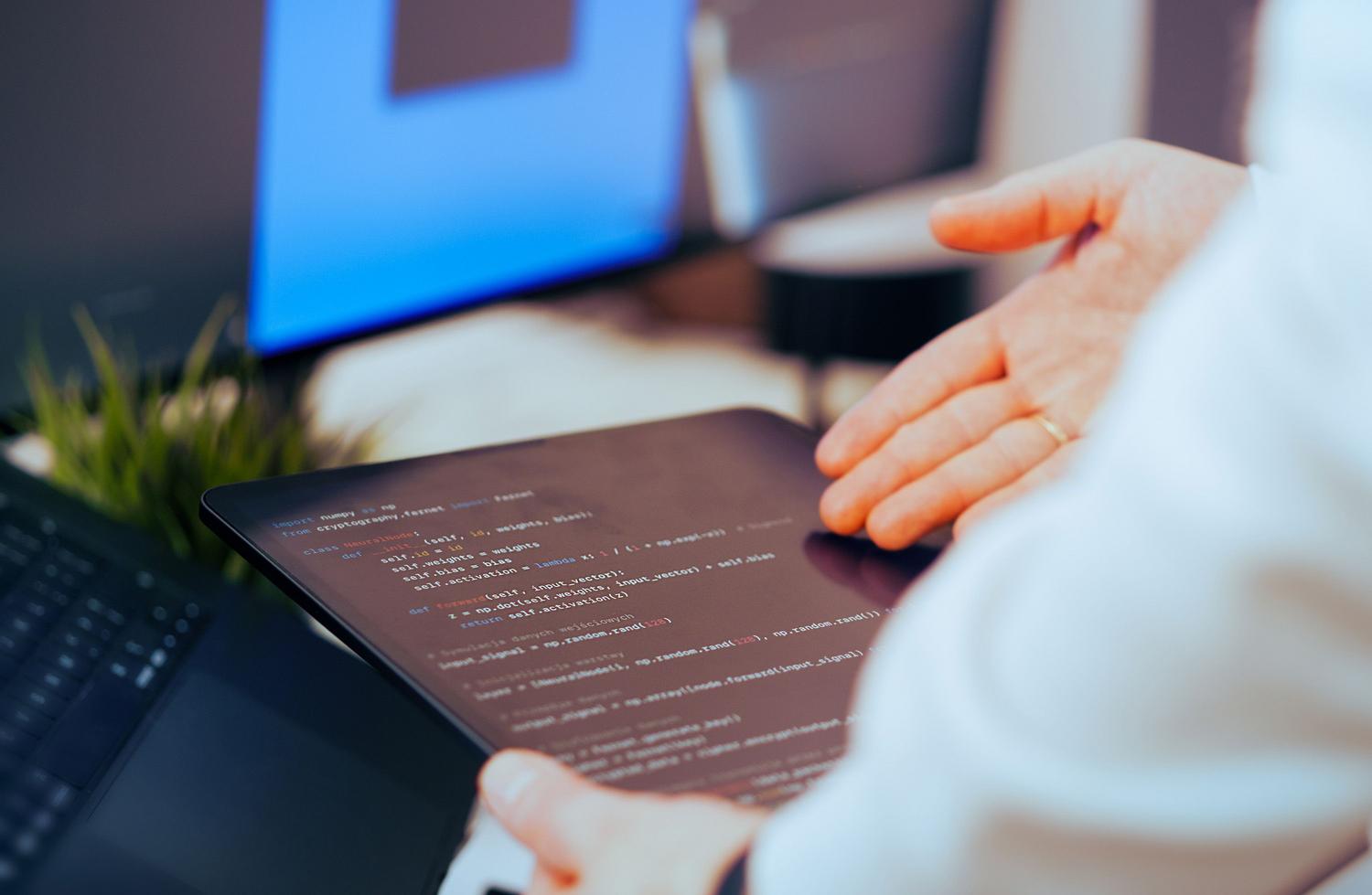 Desarrollador de software analizando detenidamente líneas de código en una tablet, simbolizando el filtro humano y la responsabilidad final sobre el código. Desarrollador de software analizando detenidamente líneas de código en una tablet, simbolizando el filtro humano y la responsabilidad final sobre el código.